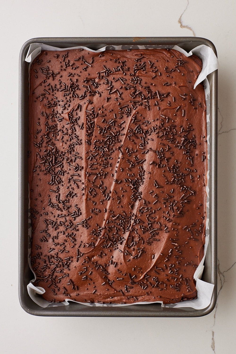 Top down view of Coca Cola Cake with frosting and chocolate sprinkles. 