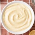 Top-dow view of a bowl of Homemade Mayonnaise with dijon mustard, lemon, egg and salt on the side.