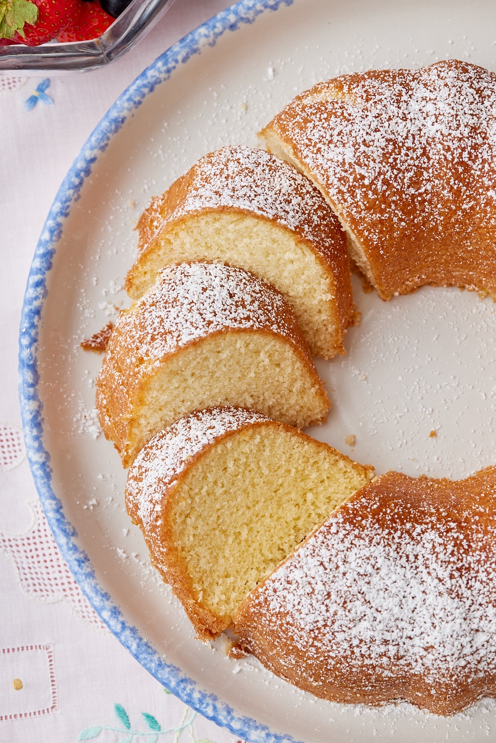 Hot Milk Cake is dusted with powdered sugar and partially sliced. 