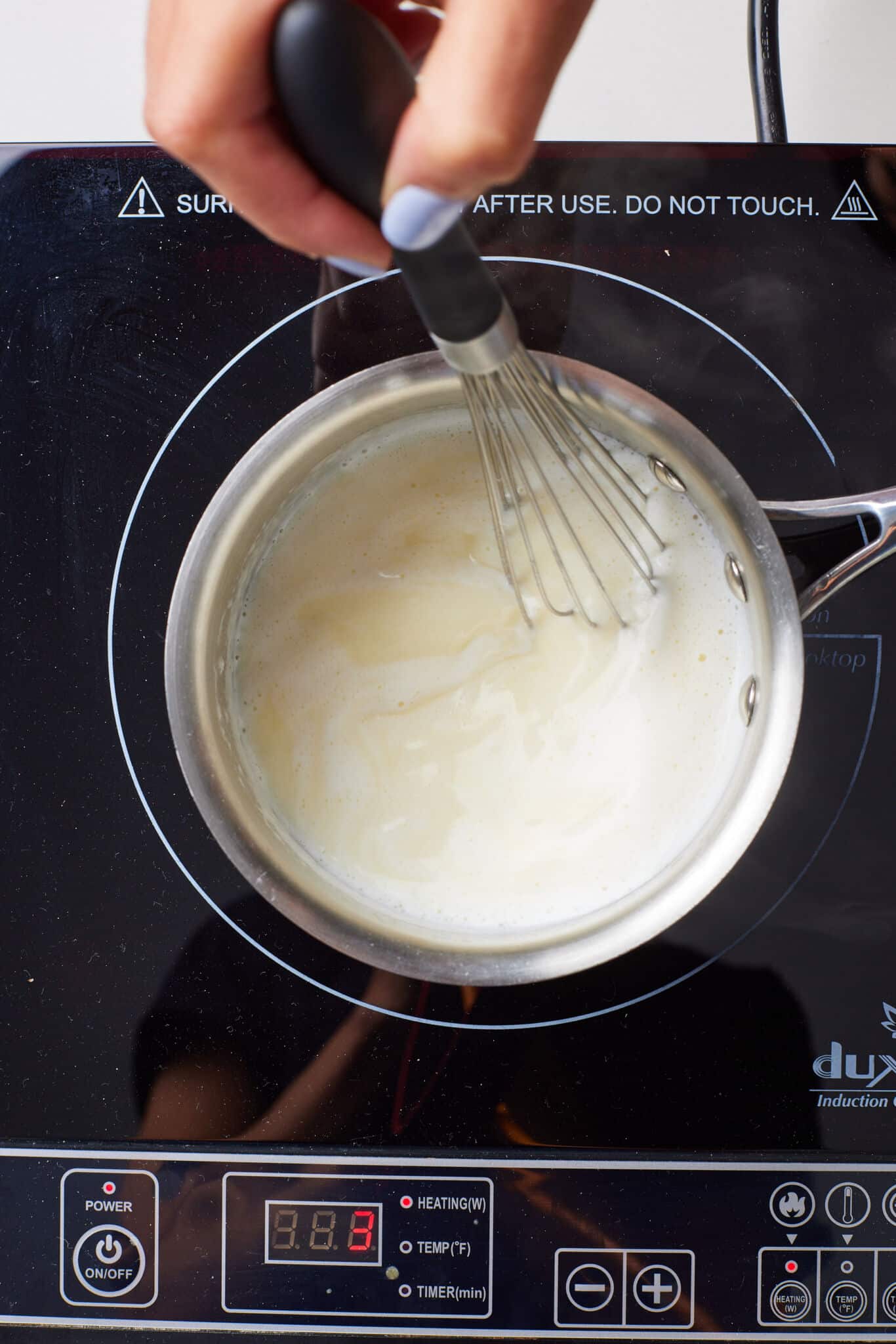 Milk is heated in the saucepan with a whisk in. Bubbles started forming around the edges. 
