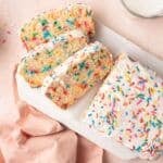 Ice Cream Bread with half loaf sliced into three slices. It's covered with icing and has sprinkle in the crumb and icing.