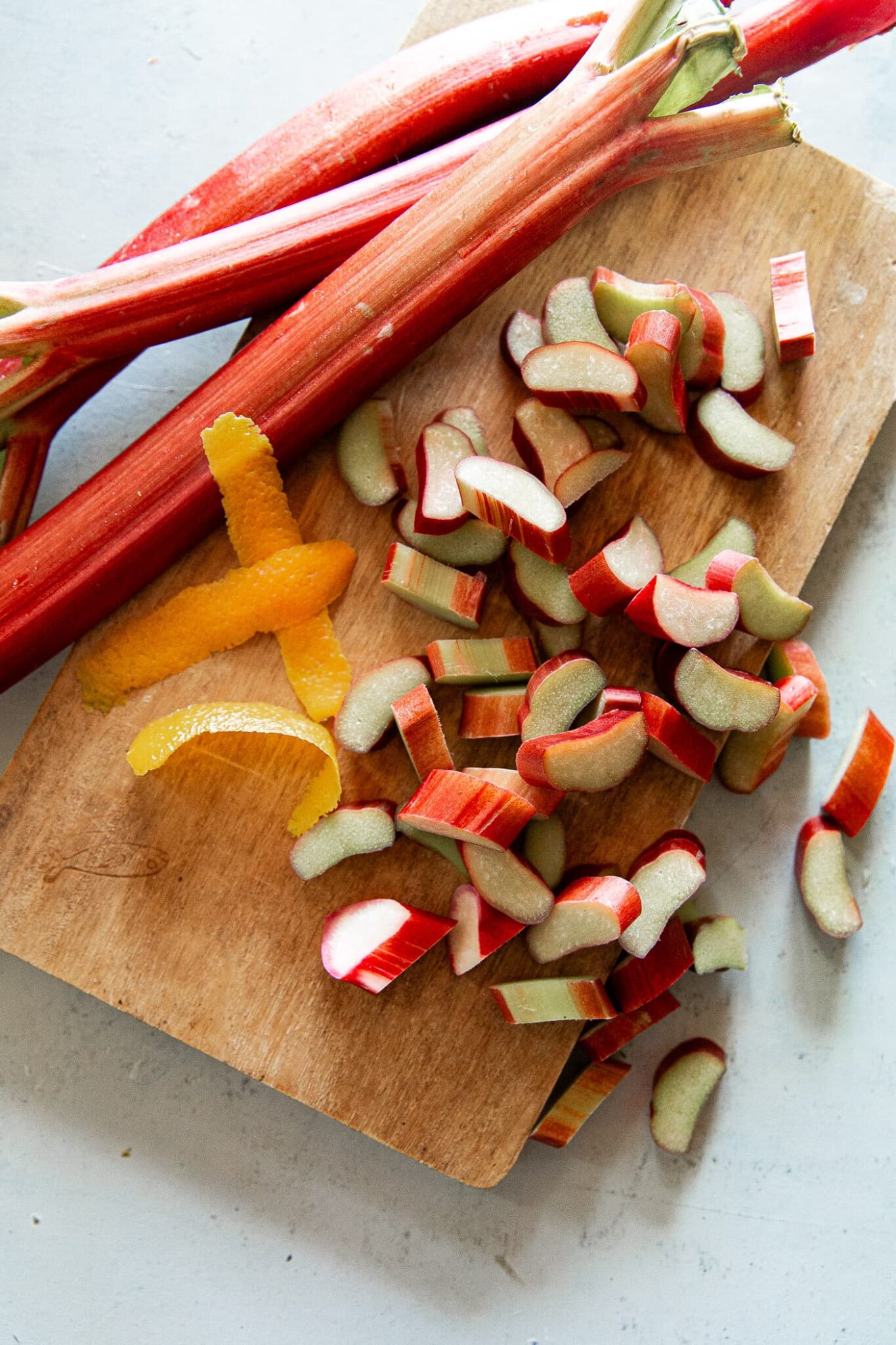 Chopped Rhubarb and Rhubarb Stalks with Orange Peel on Cutting Board