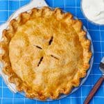Top-down view of a golden Best Apple Pie, served with softly whipped cream one the side.