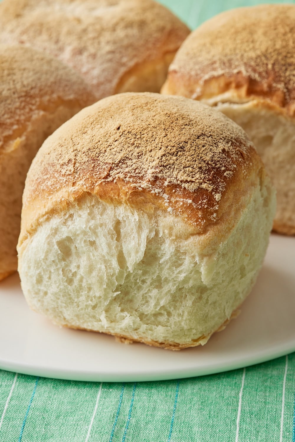 Close-up of golden-brown Irish batch loaf with four connected loaves and lightly floured, crusty tops on a white plate. 