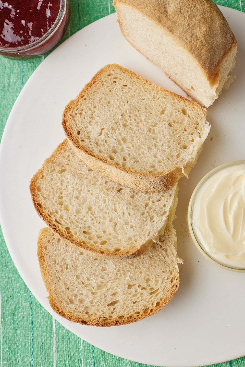 Close-up of golden-brown Irish batch loaf with four connected loaves and lightly floured, crusty tops on a white plate.